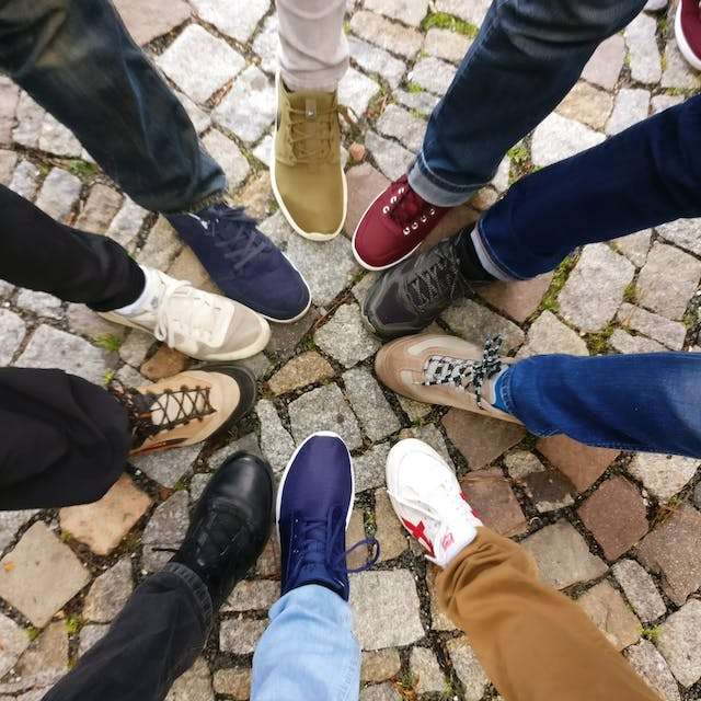 A group stands in a circle showing their shoes